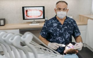 Dentist in blue floral shirt checking a patient