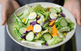 person holding a salad on a plate