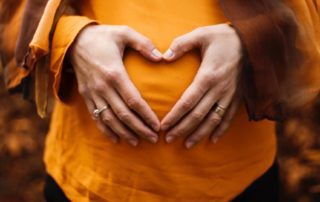 pregnant belly with hands in shape of a heart