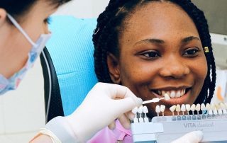 dentist holding up porcelain veneers to a patient's mouth