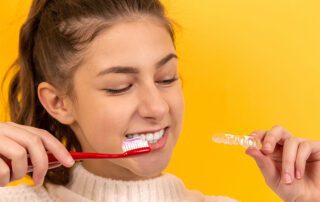 Teenager brushing teeth holding invisalign