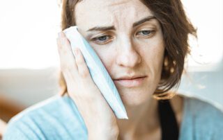 Woman holding cold compress on cheek