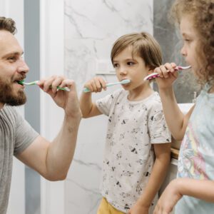 Father and children brushing teeth