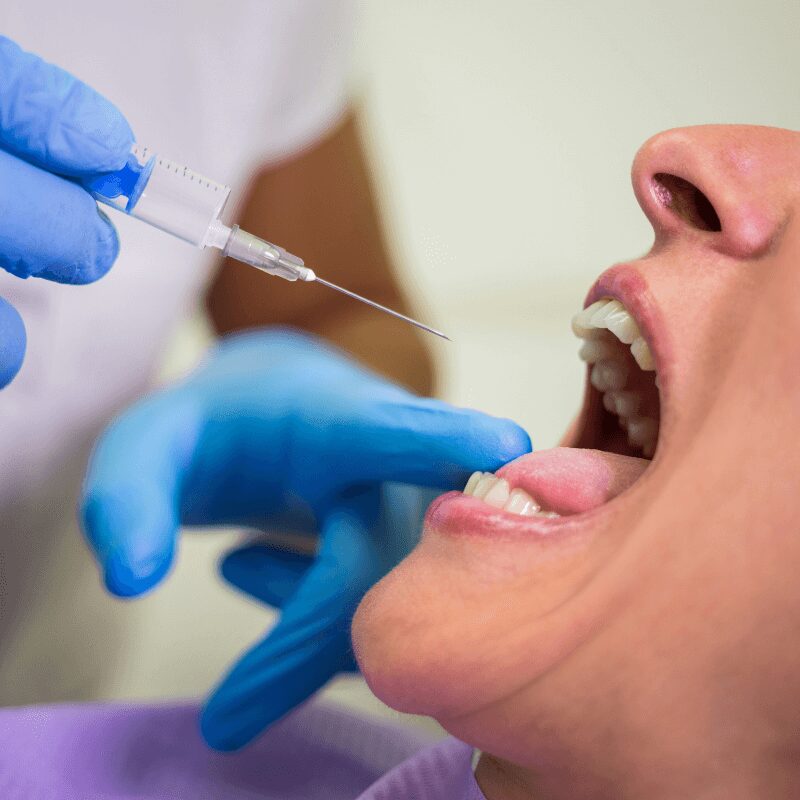 dentist giving local anasthesia injection to female patient