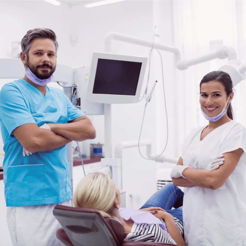 male and female dentist standing in clinic with patient in chair